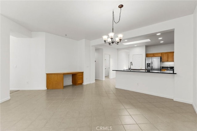 kitchen featuring pendant lighting, light tile patterned flooring, sink, stainless steel fridge, and a chandelier