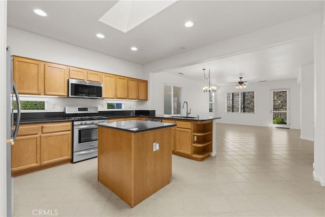 kitchen featuring ceiling fan with notable chandelier, appliances with stainless steel finishes, a center island, decorative light fixtures, and sink