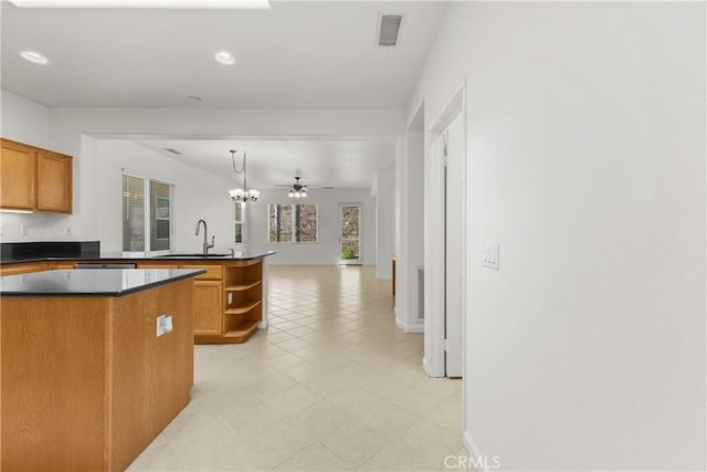 kitchen with a center island, kitchen peninsula, sink, hanging light fixtures, and ceiling fan with notable chandelier