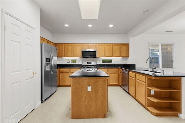 kitchen featuring sink, appliances with stainless steel finishes, a center island with sink, and a skylight