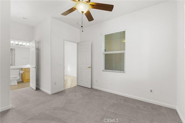 unfurnished bedroom featuring ceiling fan, light colored carpet, and ensuite bath