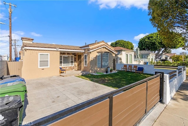 view of front of home featuring fence private yard, a front yard, and stucco siding