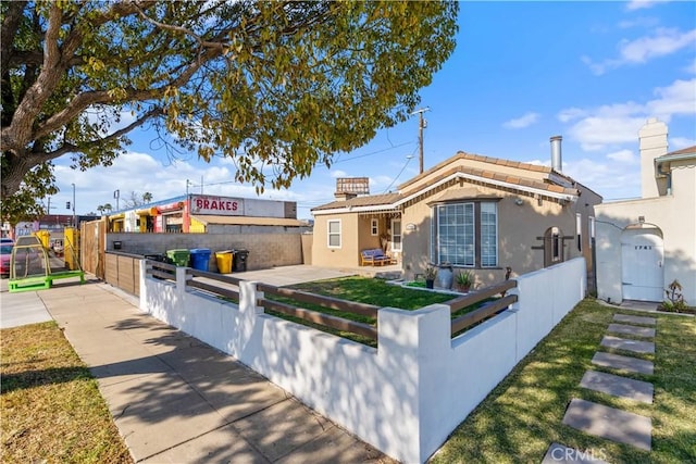 view of front of home with a fenced front yard, a gate, a tile roof, and stucco siding