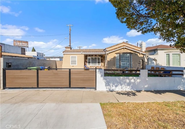 single story home featuring a fenced front yard, a gate, and stucco siding