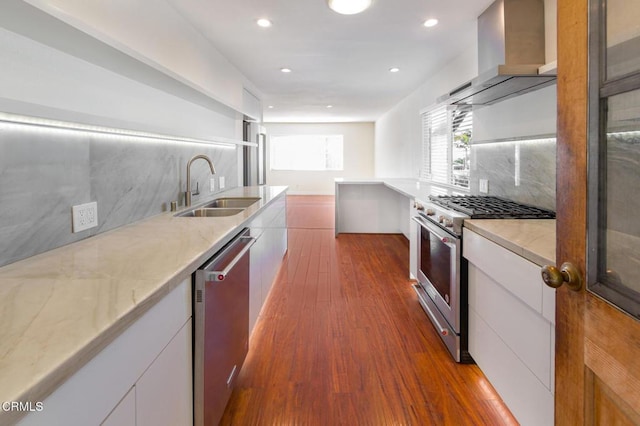 kitchen featuring backsplash, stainless steel appliances, sink, wall chimney range hood, and white cabinets