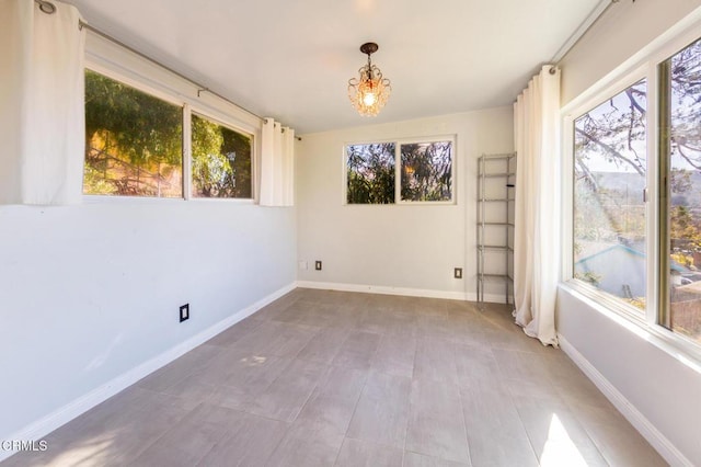 spare room featuring a healthy amount of sunlight and a chandelier