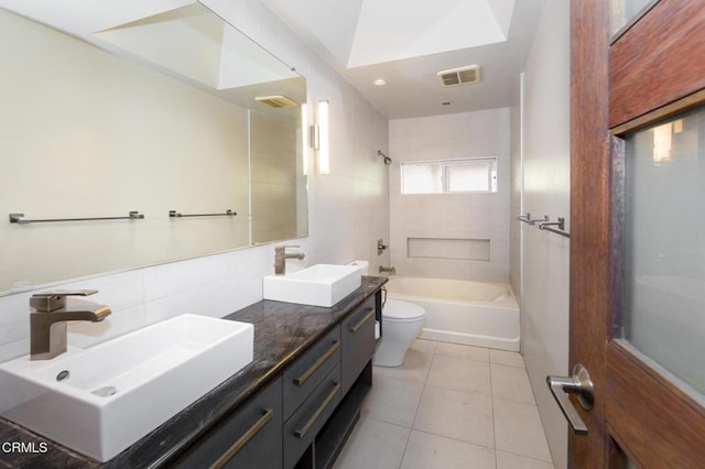 full bathroom with vanity, tile walls, tile patterned flooring, toilet, and tiled shower / bath