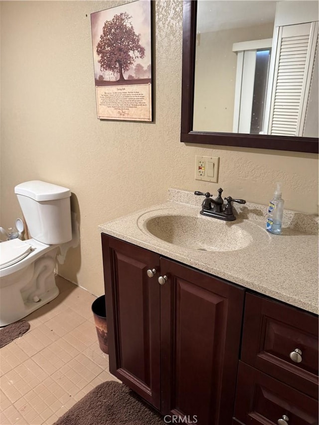 bathroom featuring toilet, vanity, and tile patterned flooring