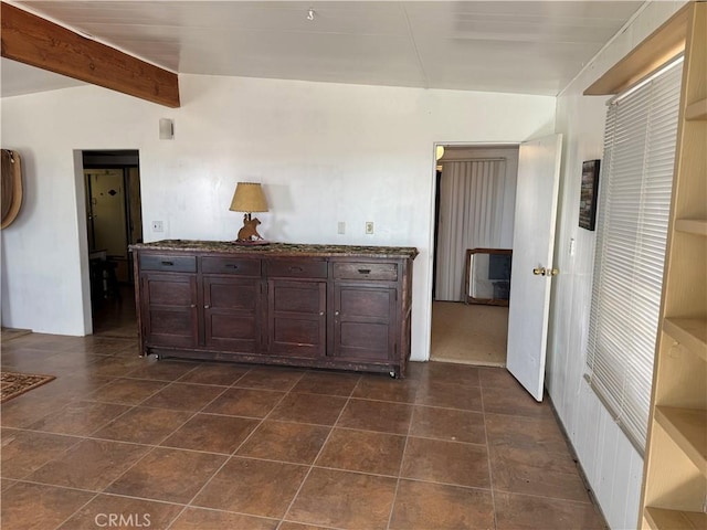 interior space featuring vaulted ceiling with beams and dark brown cabinetry