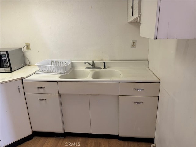 kitchen featuring white cabinetry, sink, and hardwood / wood-style floors