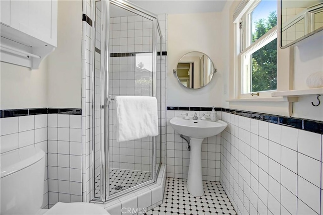 bathroom featuring tile walls, toilet, a shower with door, and a wealth of natural light