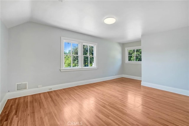 spare room featuring vaulted ceiling and light wood-type flooring