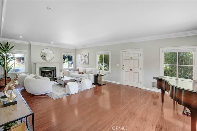 living room with a premium fireplace, ornamental molding, a healthy amount of sunlight, and wood-type flooring