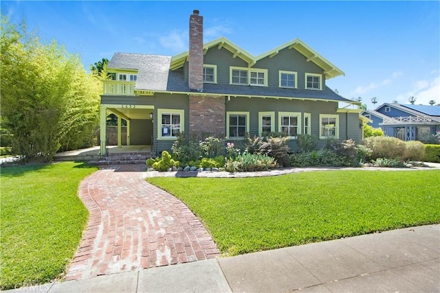 view of front facade with a balcony, a front yard, and a porch