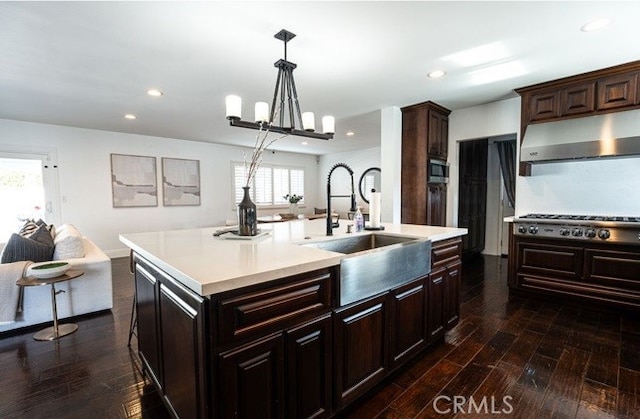 kitchen with sink, dark wood-type flooring, plenty of natural light, a center island with sink, and decorative light fixtures