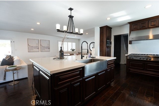 kitchen with dark wood-type flooring, sink, hanging light fixtures, plenty of natural light, and an island with sink