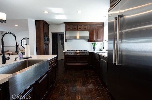 kitchen with extractor fan, sink, dark wood-type flooring, stainless steel appliances, and dark brown cabinets