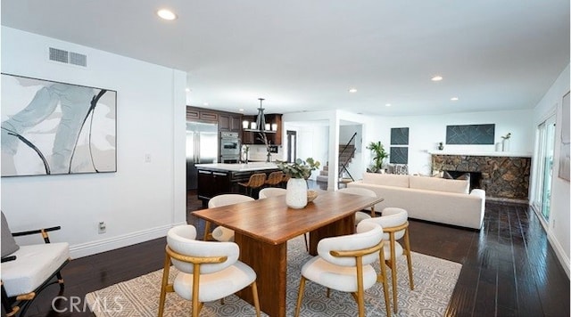 dining space featuring dark hardwood / wood-style flooring, sink, and a fireplace