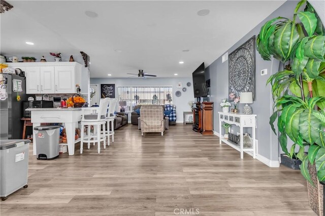 living room with ceiling fan and light wood-type flooring