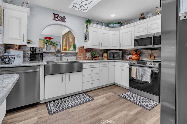 kitchen with appliances with stainless steel finishes, white cabinetry, tasteful backsplash, and sink