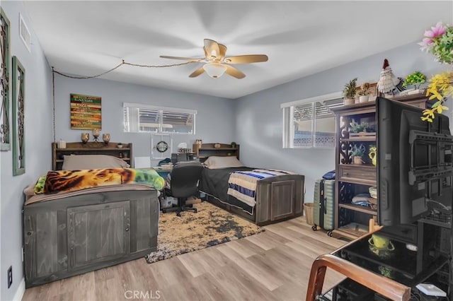 bedroom with ceiling fan, multiple windows, and light wood-type flooring