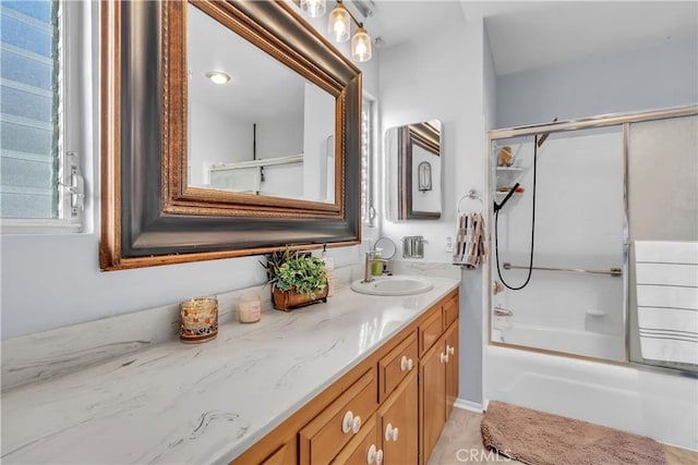 bathroom featuring combined bath / shower with glass door and vanity