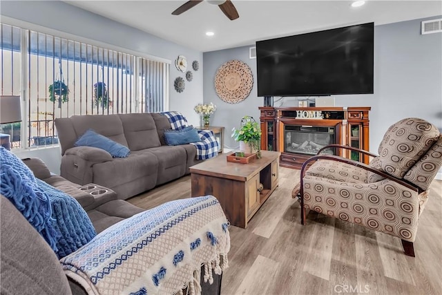 living room with ceiling fan, light wood-type flooring, and plenty of natural light