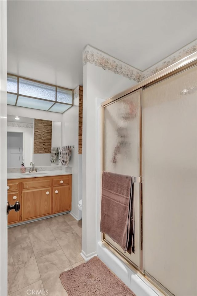 bathroom with walk in shower, vanity, and toilet