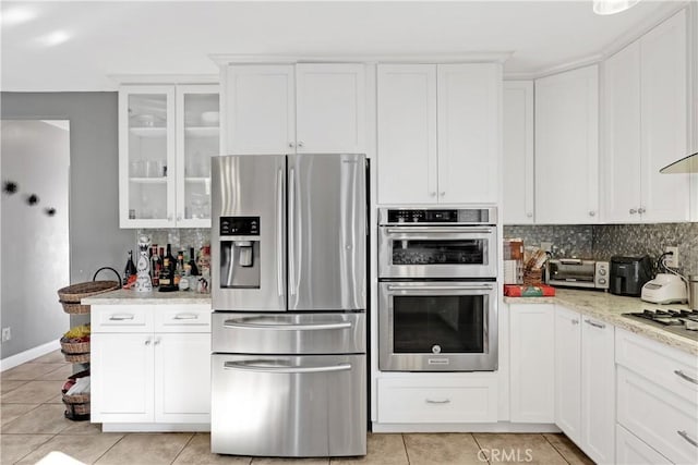 kitchen with appliances with stainless steel finishes, white cabinets, tasteful backsplash, and light stone countertops