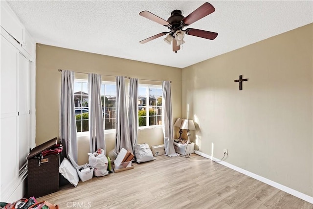 miscellaneous room featuring a textured ceiling, ceiling fan, and light hardwood / wood-style flooring