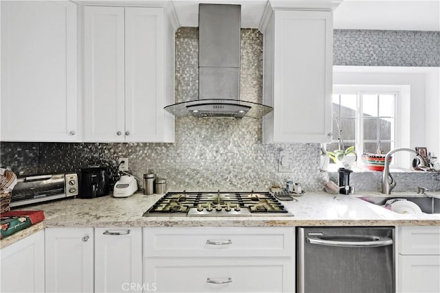 kitchen with stainless steel appliances, sink, white cabinets, and wall chimney range hood