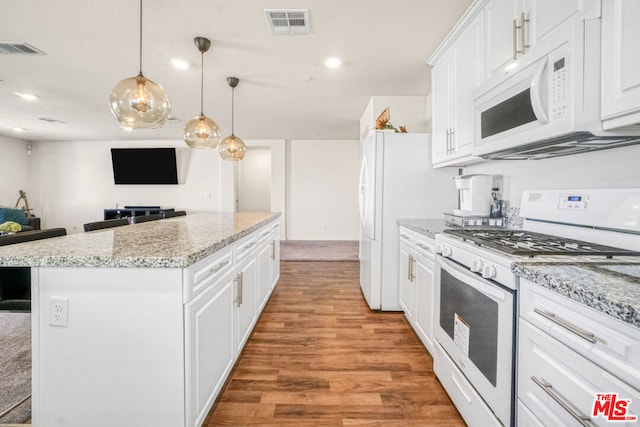 kitchen with white appliances, white cabinets, a kitchen island, decorative light fixtures, and light stone counters