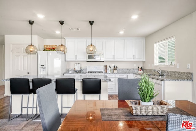 kitchen featuring white cabinetry, sink, white appliances, and pendant lighting