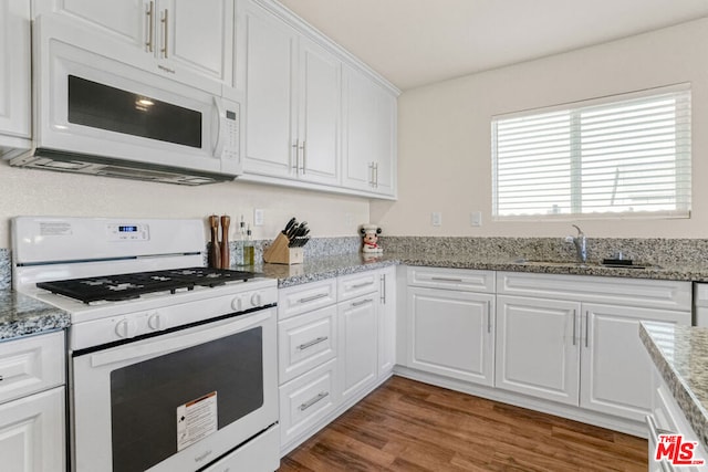 kitchen featuring white cabinetry, sink, white appliances, and light stone countertops