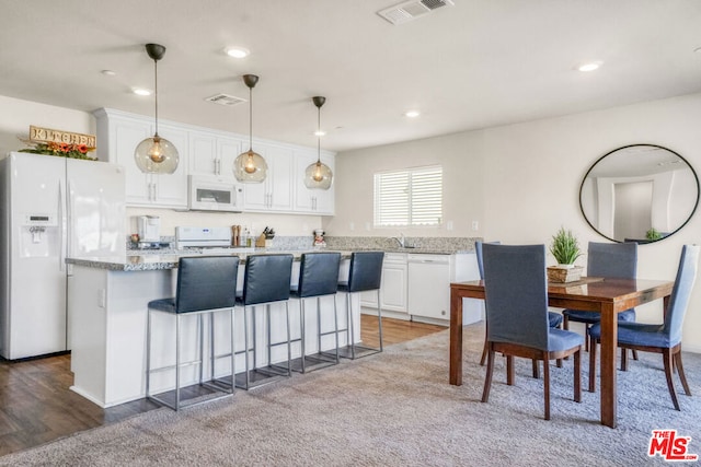 kitchen featuring decorative light fixtures, white appliances, white cabinetry, and a kitchen island