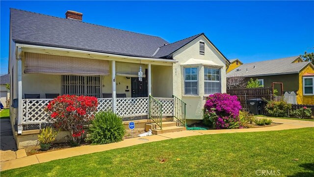 rear view of property with covered porch and a yard