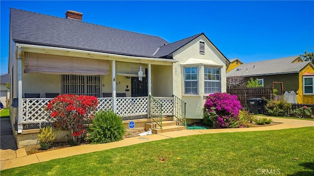 rear view of house featuring covered porch and a yard