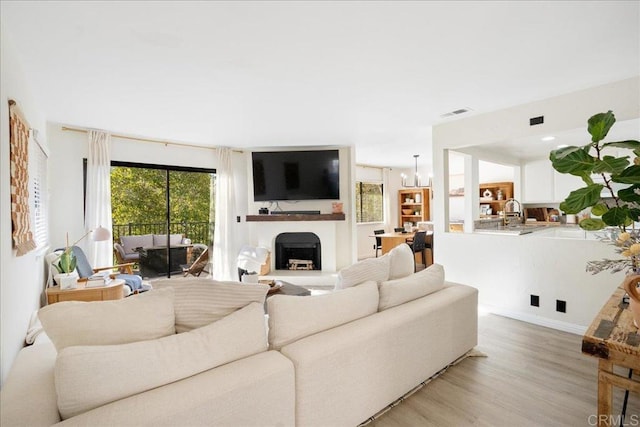 living room featuring light wood-style floors, a fireplace, and an inviting chandelier