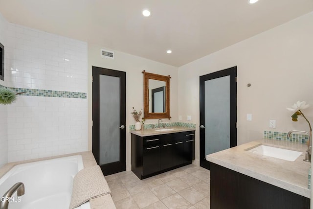 bathroom featuring tile patterned floors, vanity, and a bath