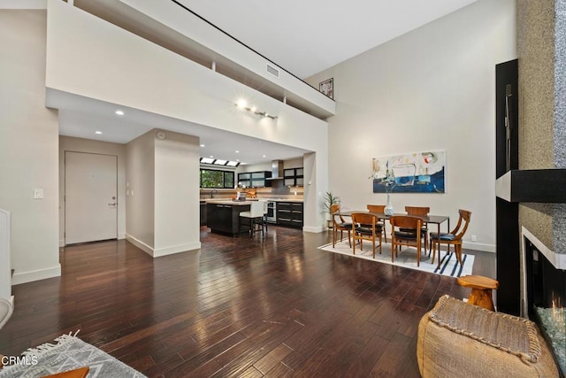 living room featuring sink, dark wood-type flooring, and a high ceiling