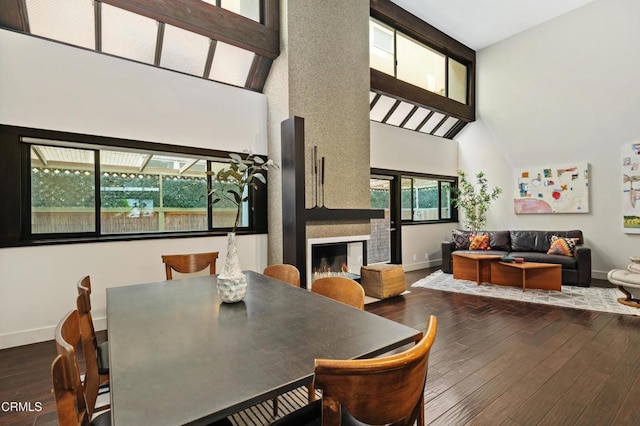 dining space featuring hardwood / wood-style flooring, a large fireplace, and high vaulted ceiling