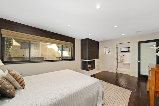 bedroom featuring dark hardwood / wood-style flooring and a large fireplace