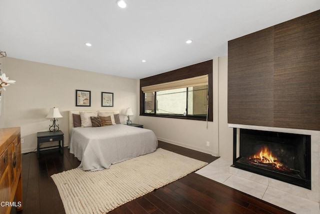 bedroom with wood-type flooring and a tile fireplace