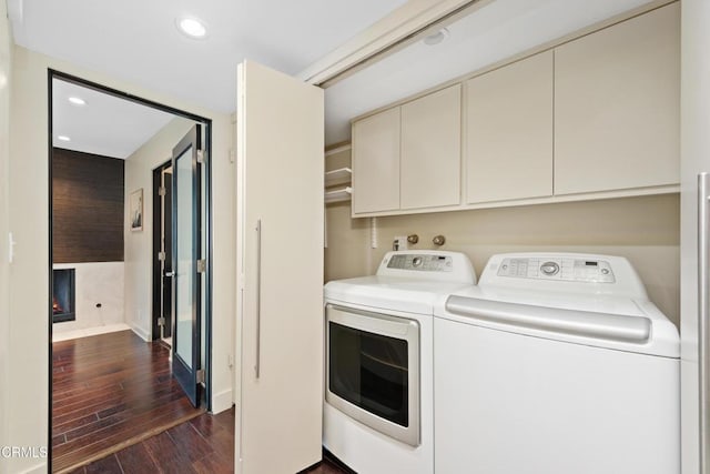 washroom featuring dark hardwood / wood-style flooring, washer and clothes dryer, and cabinets