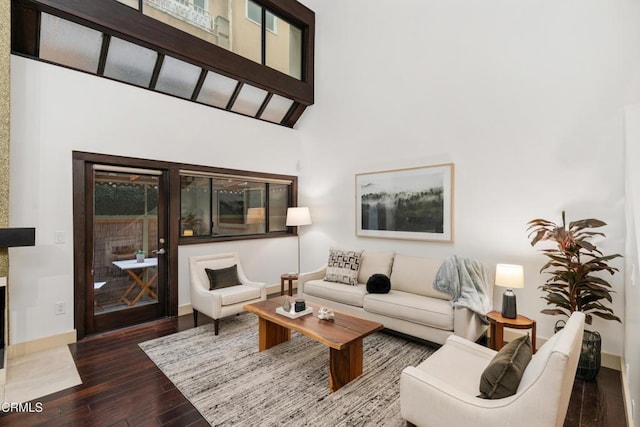 living area featuring baseboards, a high ceiling, and hardwood / wood-style floors