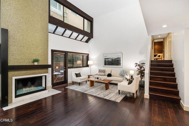 living room featuring a fireplace with flush hearth, stairs, a high ceiling, and wood finished floors