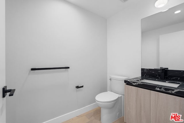 bathroom with toilet, wood-type flooring, and vanity