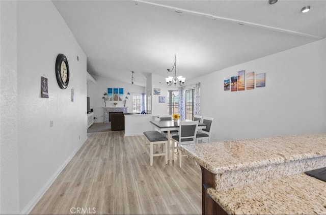 dining area featuring hardwood / wood-style flooring, a chandelier, lofted ceiling, and a brick fireplace