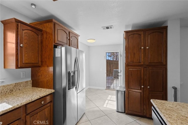 kitchen with light stone countertops, stainless steel fridge, and light tile patterned flooring