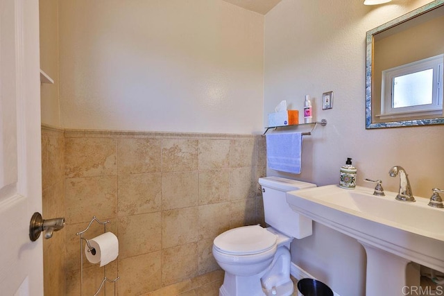 bathroom with sink, tile walls, and toilet